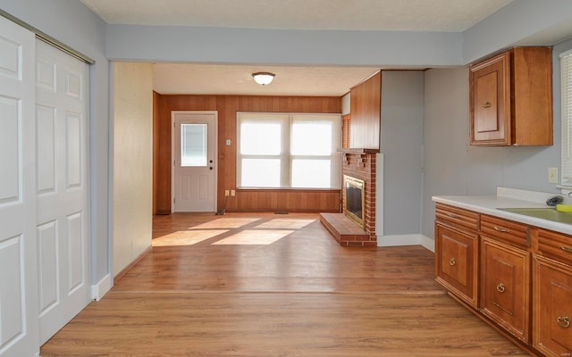 kitchen with a textured ceiling, light wood-type flooring, and a brick fireplace