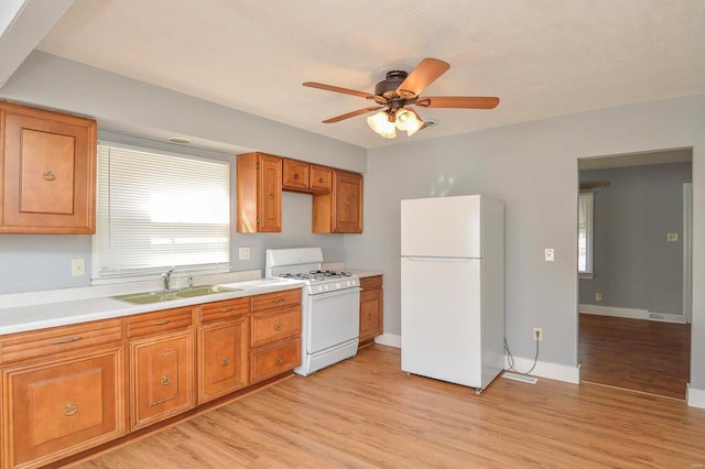 kitchen featuring light wood-type flooring, white appliances, ceiling fan, and sink