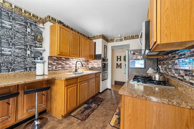 kitchen featuring dark tile patterned flooring, sink, decorative backsplash, light stone countertops, and appliances with stainless steel finishes