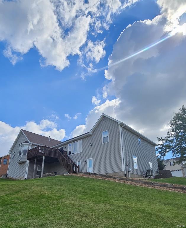 rear view of property featuring a yard and a wooden deck