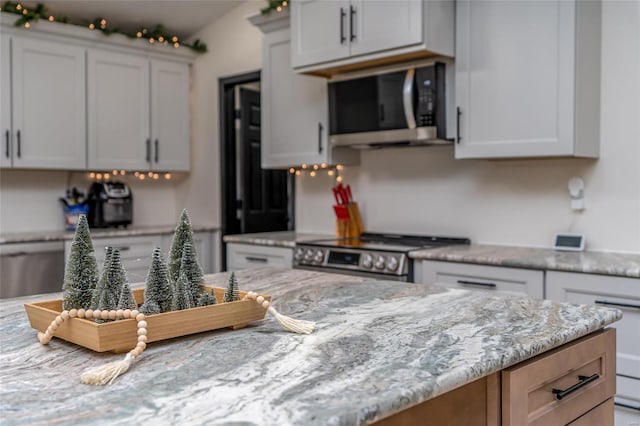 kitchen with light stone countertops, white cabinetry, and stainless steel appliances