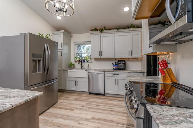 kitchen with white cabinetry, stainless steel appliances, light hardwood / wood-style flooring, a notable chandelier, and lofted ceiling