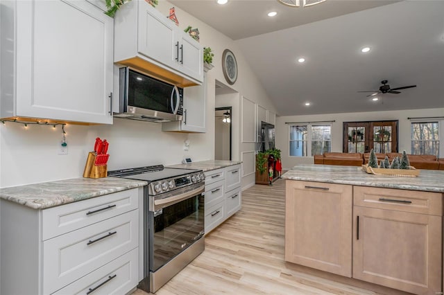 kitchen featuring appliances with stainless steel finishes, light wood-type flooring, white cabinetry, and lofted ceiling