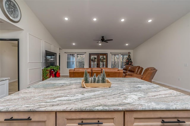 kitchen featuring vaulted ceiling, ceiling fan, light stone countertops, light brown cabinetry, and wood-type flooring