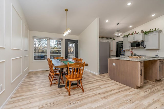 dining room featuring light wood-type flooring and vaulted ceiling