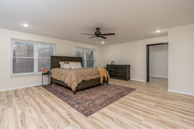 bedroom with ceiling fan, light wood-type flooring, and multiple windows