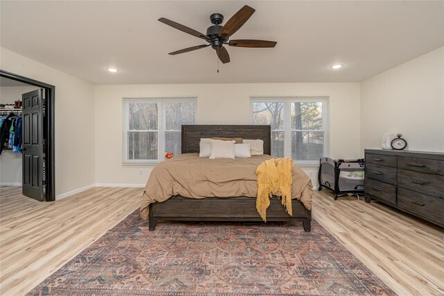 bedroom featuring a walk in closet, ceiling fan, a closet, and hardwood / wood-style flooring