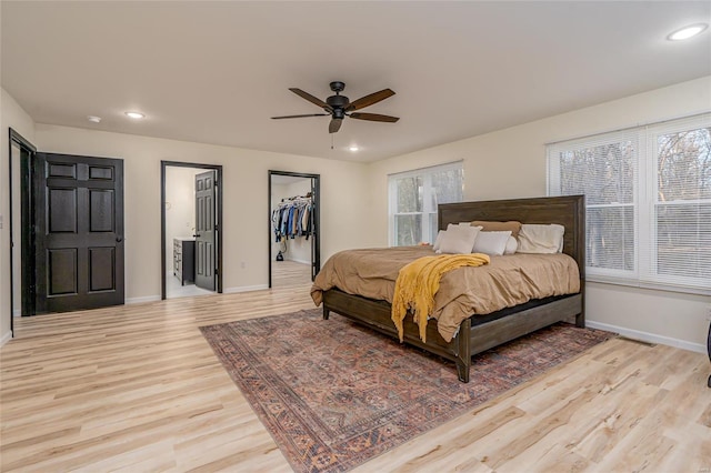 bedroom with a closet, a walk in closet, light hardwood / wood-style floors, and ceiling fan