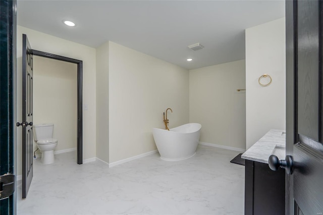 bathroom with a washtub, vanity, and toilet