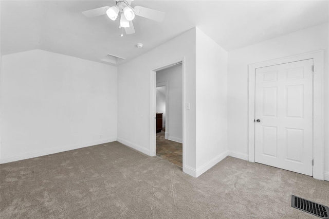 unfurnished bedroom featuring lofted ceiling, light colored carpet, visible vents, a ceiling fan, and baseboards