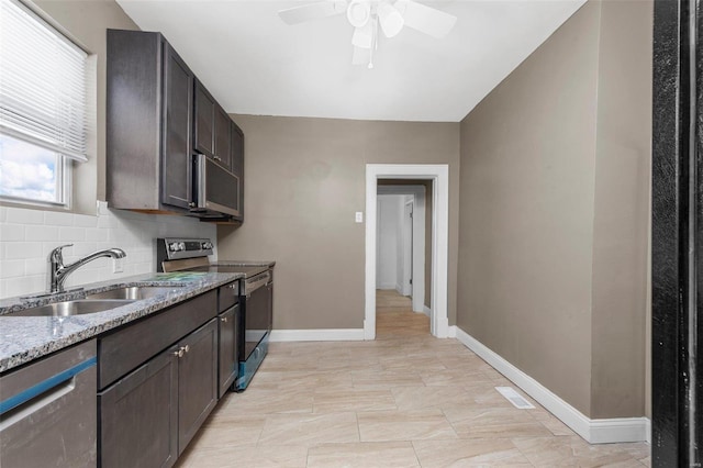 kitchen with light stone counters, stainless steel appliances, tasteful backsplash, a sink, and dark brown cabinetry