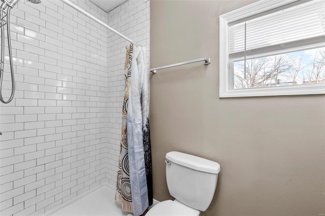 bathroom featuring tiled shower and toilet