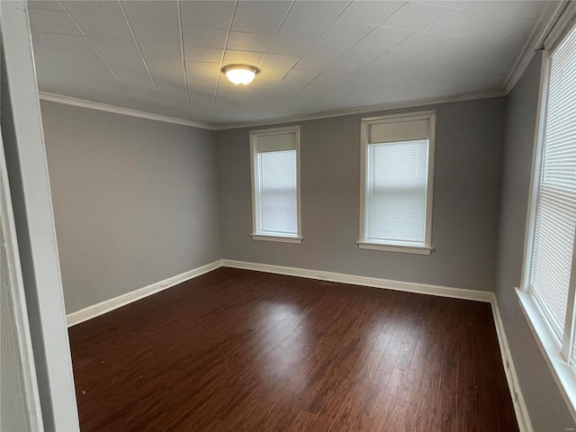 spare room with ornamental molding, plenty of natural light, and dark wood-type flooring