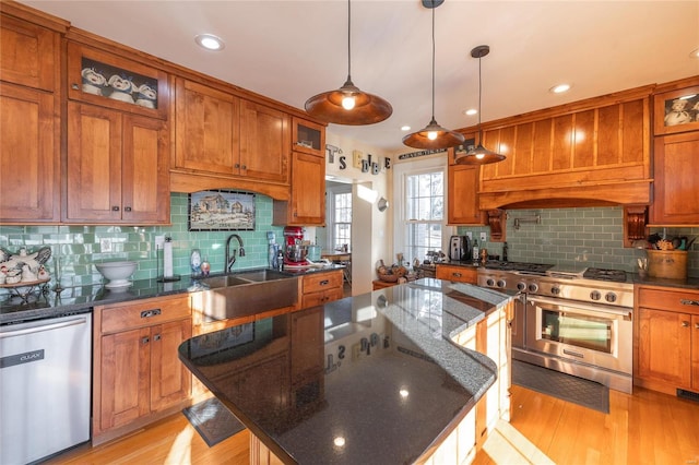 kitchen with sink, a kitchen island, stainless steel appliances, and light wood-type flooring