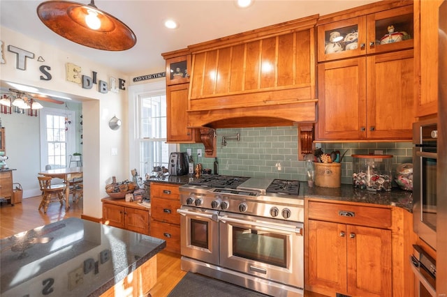 kitchen with appliances with stainless steel finishes, light wood-type flooring, backsplash, ceiling fan, and pendant lighting