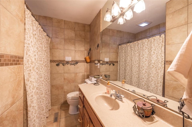 bathroom with vanity, tile patterned floors, a shower with shower curtain, toilet, and tile walls