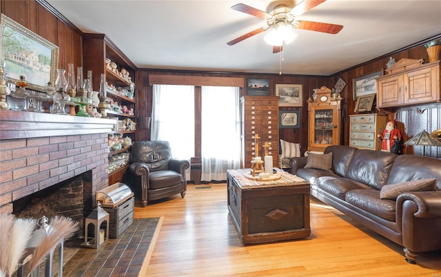 living room with light hardwood / wood-style floors, ceiling fan, ornamental molding, and wood walls