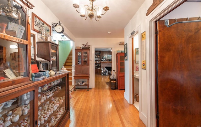 hall featuring light wood-type flooring and an inviting chandelier