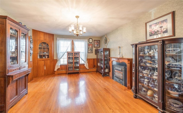 miscellaneous room with a fireplace, wood walls, light hardwood / wood-style flooring, and a chandelier