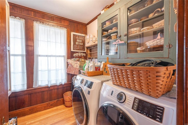 laundry room featuring wood walls, washer and clothes dryer, ornamental molding, and light hardwood / wood-style flooring