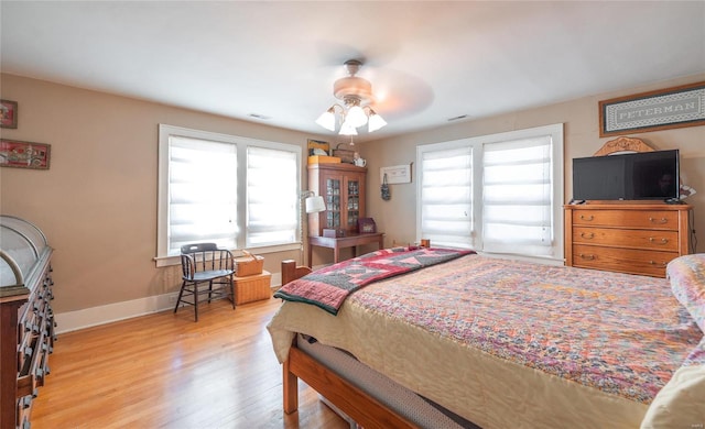 bedroom with multiple windows, ceiling fan, and wood-type flooring