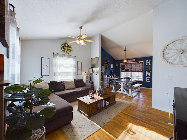 living room featuring ceiling fan with notable chandelier, a textured ceiling, light hardwood / wood-style floors, and high vaulted ceiling