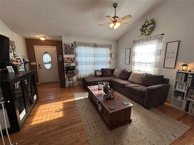 living room with a textured ceiling, ceiling fan, hardwood / wood-style floors, and vaulted ceiling