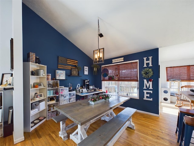 dining area featuring light wood-type flooring, high vaulted ceiling, and an inviting chandelier