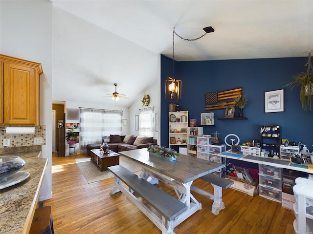 dining area with ceiling fan, high vaulted ceiling, and light hardwood / wood-style flooring