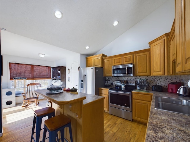 kitchen featuring sink, stainless steel appliances, a kitchen breakfast bar, light hardwood / wood-style floors, and a kitchen island