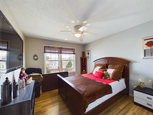 bedroom with ceiling fan, hardwood / wood-style floors, and a textured ceiling