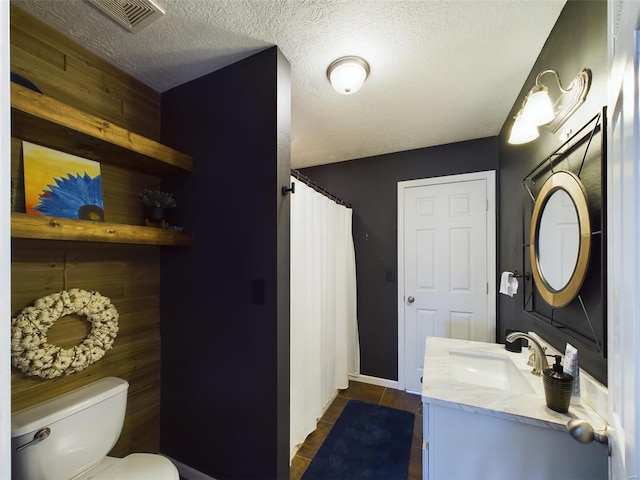 bathroom with vanity, a textured ceiling, and toilet