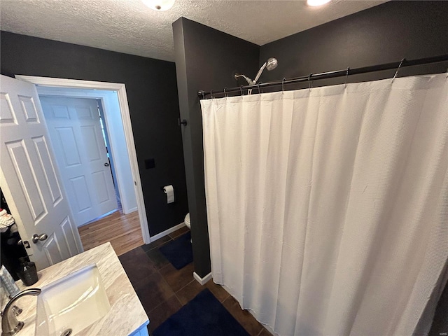 bathroom featuring a shower with shower curtain, a textured ceiling, vanity, hardwood / wood-style floors, and toilet