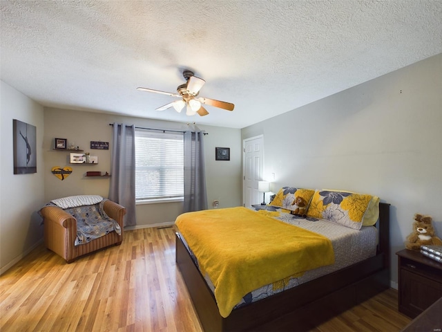 bedroom featuring ceiling fan, light hardwood / wood-style flooring, and a textured ceiling