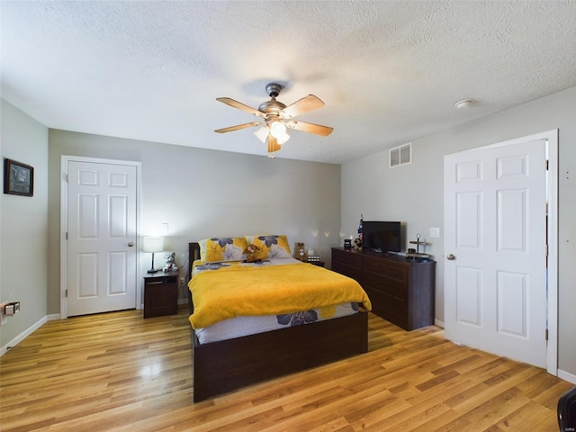 bedroom featuring a textured ceiling, light wood-type flooring, and ceiling fan