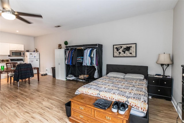 bedroom featuring white refrigerator, light hardwood / wood-style flooring, and ceiling fan