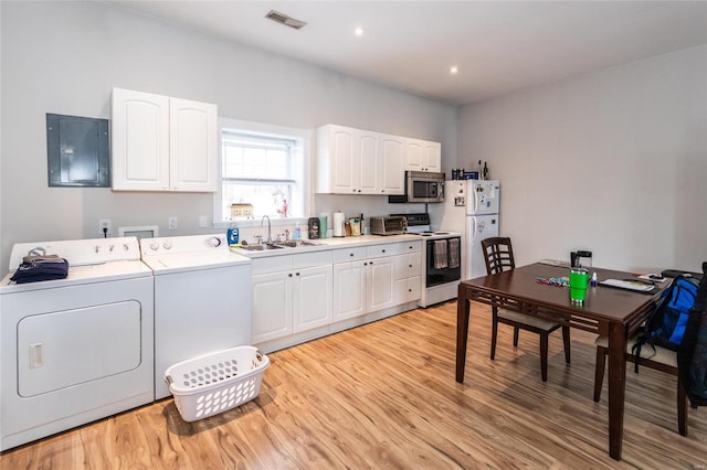 clothes washing area featuring washer and dryer, light wood-type flooring, electric panel, and sink