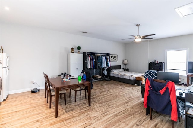 bedroom with ceiling fan, white fridge, and light hardwood / wood-style floors