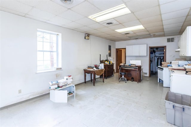 interior space featuring a paneled ceiling and white cabinets