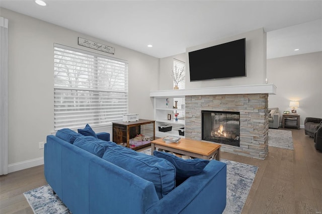 living room with hardwood / wood-style floors and a stone fireplace