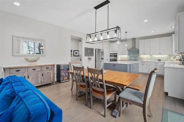 dining space with sink, light hardwood / wood-style floors, and beverage cooler