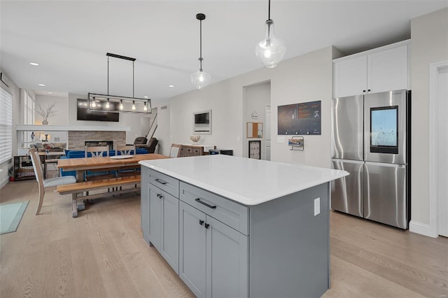 kitchen featuring a stone fireplace, pendant lighting, stainless steel refrigerator, and a center island