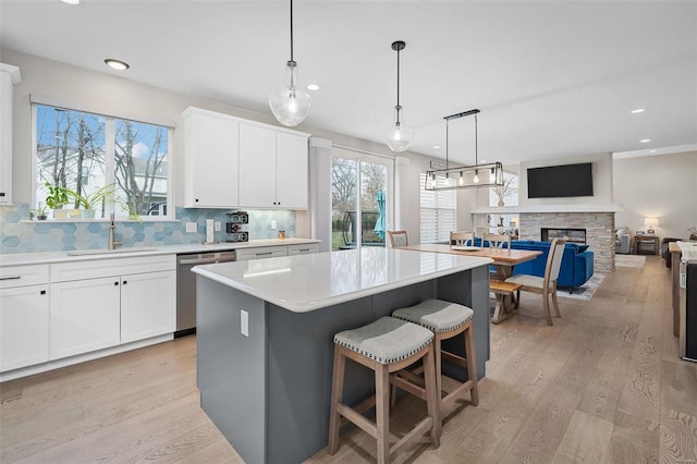 kitchen featuring dishwasher, decorative backsplash, a kitchen island, sink, and white cabinetry