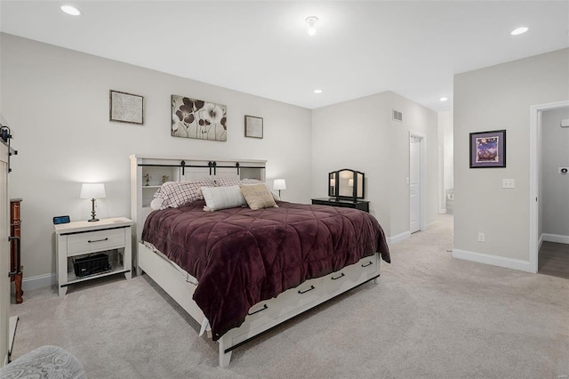 bedroom with a barn door and light colored carpet