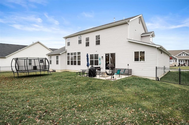 rear view of house featuring a patio, a trampoline, and a lawn