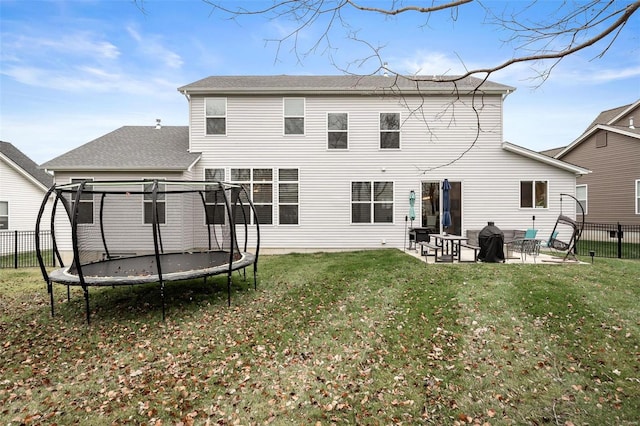 back of property featuring a yard, a trampoline, and a patio area