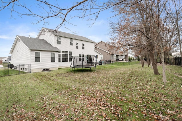 back of property featuring a trampoline and a lawn