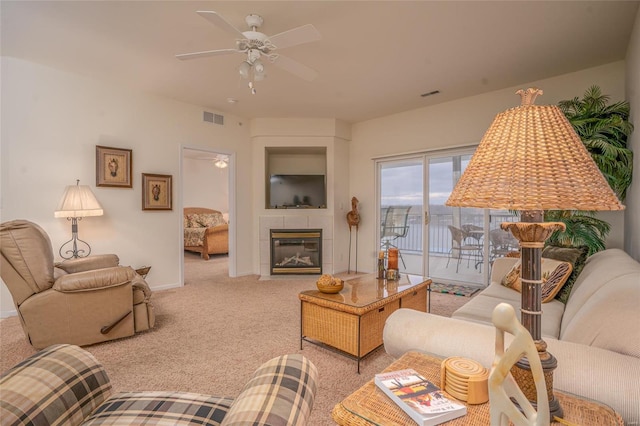 living room featuring ceiling fan, light carpet, and a tile fireplace