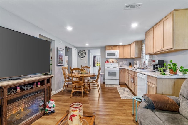 kitchen with sink, light brown cabinets, white appliances, and light wood-type flooring