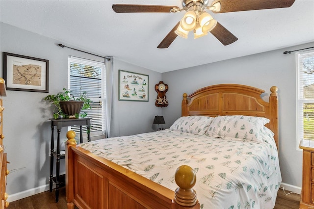 bedroom with multiple windows, dark hardwood / wood-style floors, and ceiling fan